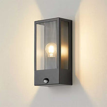 Load image into Gallery viewer, Wall-mounted outdoor light fixture with glass cover on a white wall.
